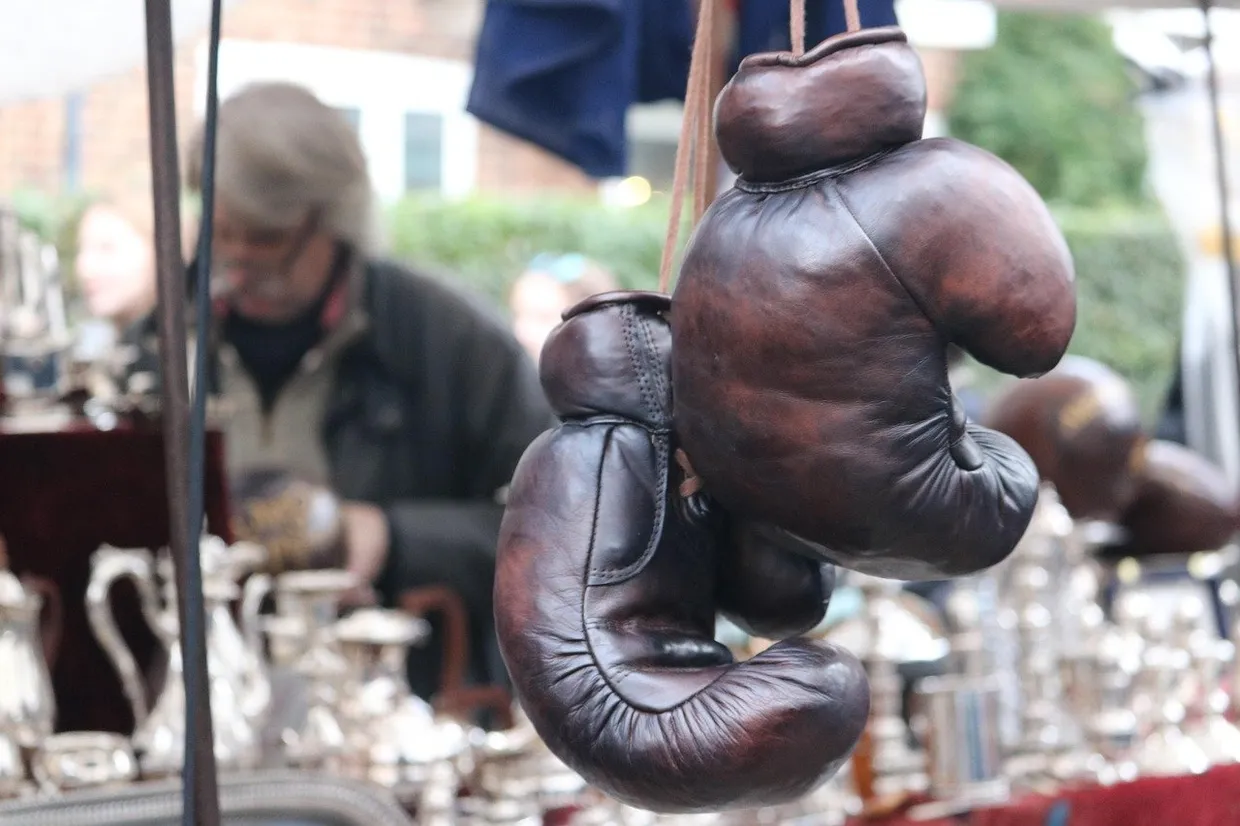 Par de guantes de boxeo antiguos de cuero marrón colgados en un puesto de mercadillo